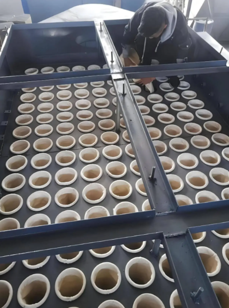 工人正在小心翼翼地将袋笼垂直插入已经放入花板孔的滤袋中